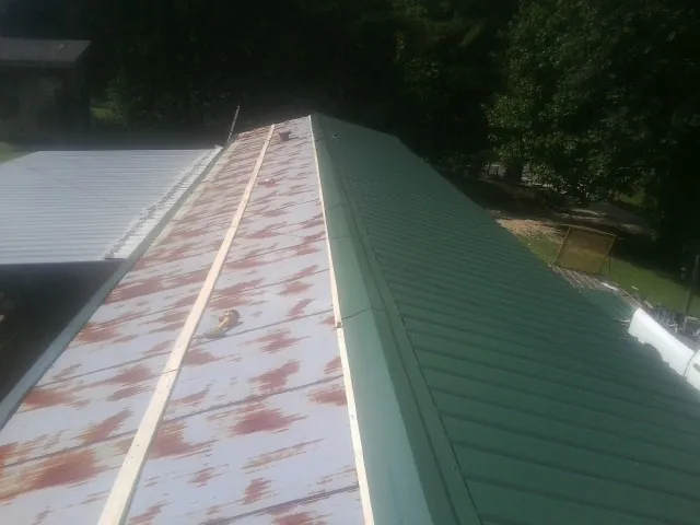 Old rusted panels beside newly installed green metal roofing — Wind Damage Roof Repair by Roofing Brothers in Garden Prairie