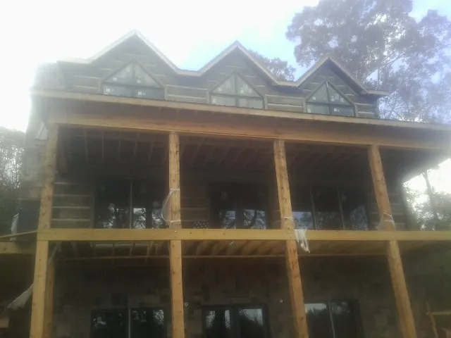 Dormers and porch framing on a large log home under construction — Roof Coating work by our crew in Garden Prairie