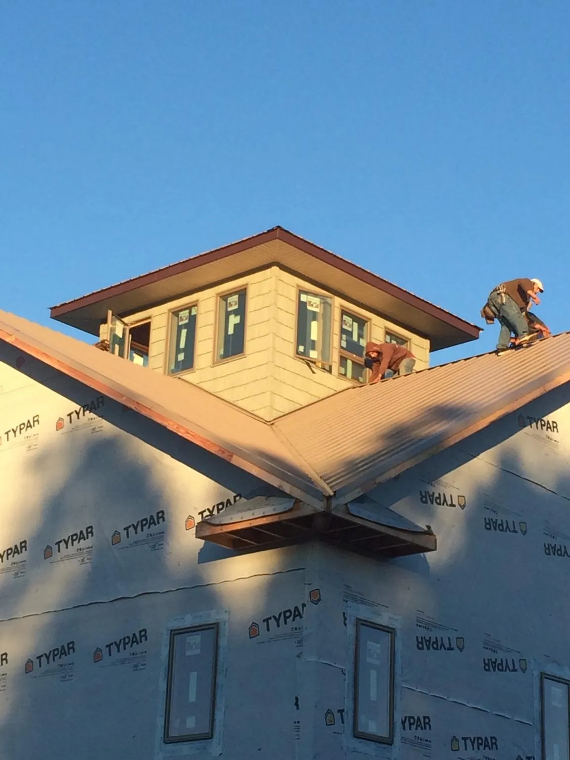 Roofers working around a rooftop cupola on a new metal roof at sunset — Roof Waterproofing in Garden Prairie by Roofing Brothers